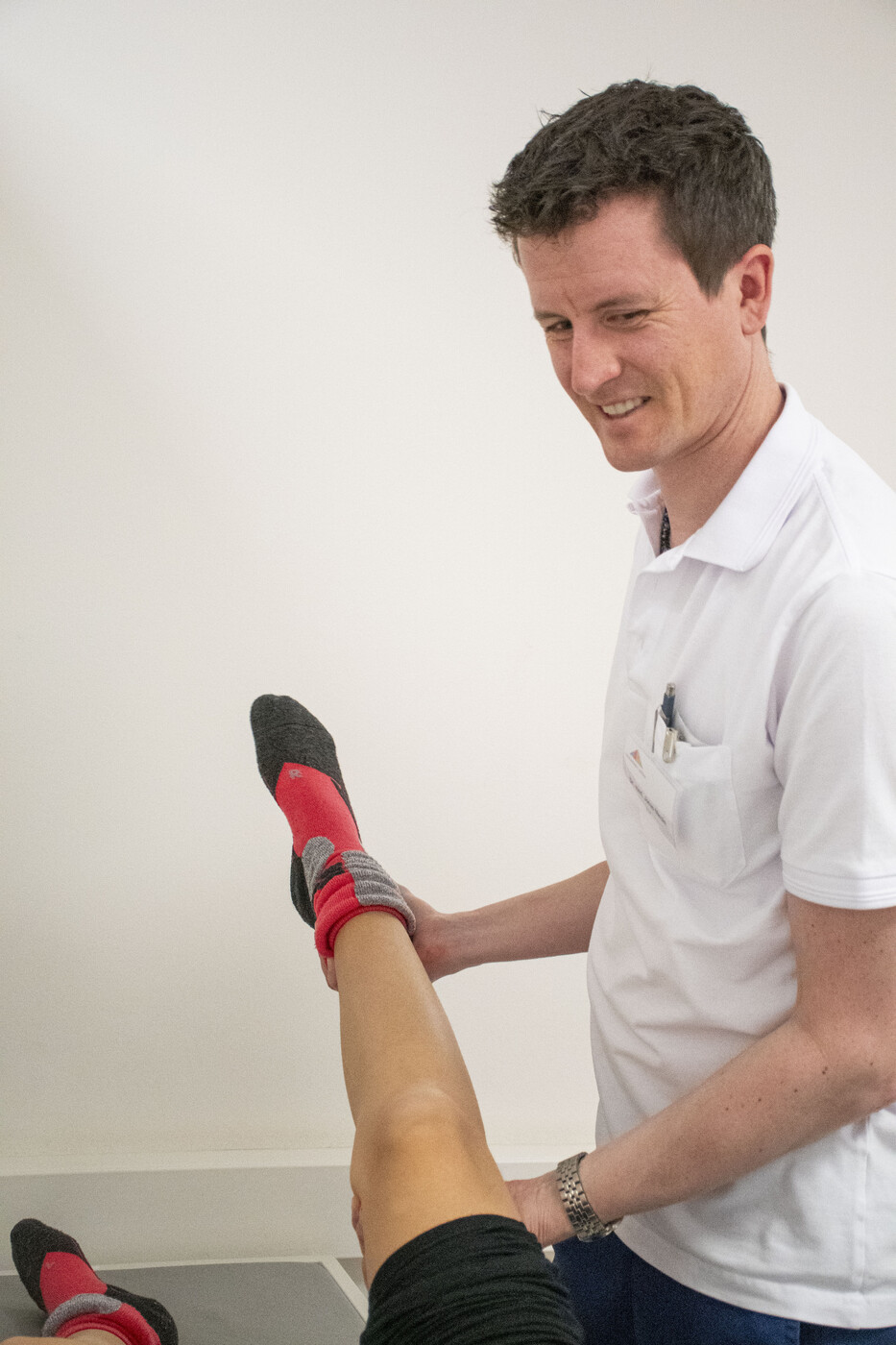 Jonas Maxén, leitender Arzt des medizinischen Zentrums, testet die Reflexe der Bänder nach einem Skiunfall.