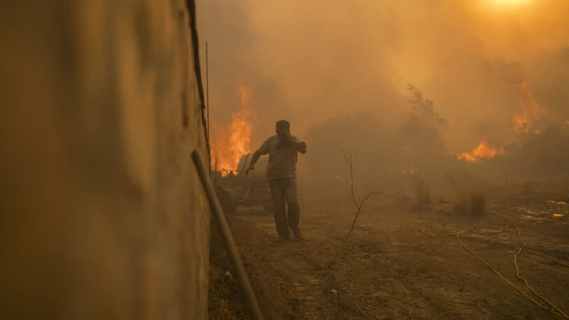 Ein Einheimischer flieht vor den Flammen von einem Waldbrand im Dorf Gennadi auf der griechischen Insel Rhodos. Foto: Petros Giannakouris/AP/dpa