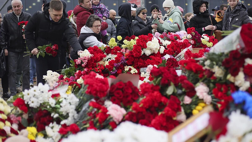 dpatopbilder - Menschen legen Blumen vor der Crocus City Hall nieder. In der Konzerthalle in einem Moskauer Vorort hatten Bewaffnete das Feuer auf Konzertbesucher eröffnet. Die Zahl der Todesopfer stieg laut russischen Behörden über 135. Foto: Vitaly…
