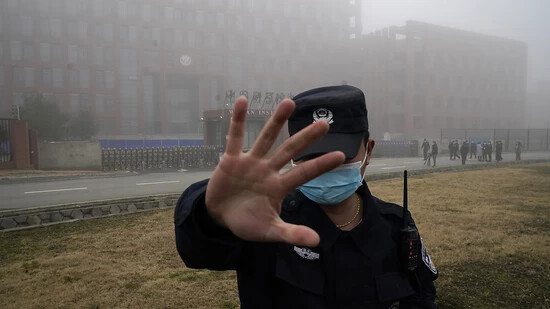 ARCHIV - Eine Sicherheitsperson vom Wuhan Instituts für Virologie (WIV) hindert Journalisten an ihrer Arbeit nachdem ein Team der Weltgesundheitsorganisation (WHO) eintraf (Archivbild). Foto: Ng Han Guan/AP/dpa
