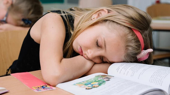 Lernen im Schlaf: Ein Mädchen hat den Kampf gegen die Müdigkeit verloren und ist während des Unterrichts eingeschlafen.