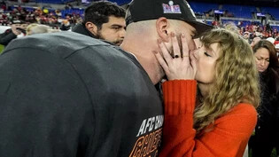 ARCHIV - Die Musikerin Taylor Swift (r) küsst Kansas City Chiefs Tight End Travis Kelce nach einem NFL-Footballspiel auf dem Spielfeld. Foto: Julio Cortez/AP/dpa