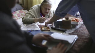 Eine Frau füllt ihren Stimmzettel für die Präsidentenwahl aus, während sie von einem mobilen Wahlkomitee besucht wird. Foto: Uncredited/AP/dpa