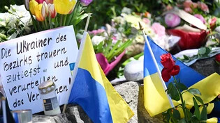 dpatopbilder - Neben dem Einkaufszentrums, an dem zwei Männer aus der Ukraine getötet worden sind, haben Menschen Blumen und Plakate niedergelegt. Foto: Angelika Warmuth/dpa