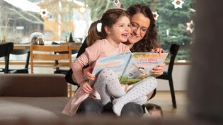 Die Mutter Flurina Eschmann liest mit ihrer Tochter Adriana vergnügt ein Buch: Der kleine Sonnenschein Adriana ist trotz der seltenen Krankheit Tatton-Brown-Rahman-Syndrom (TBRS) ein fröhliches Kind.