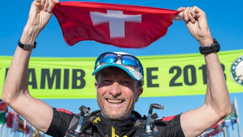 Roberto Rivola hält in der Sahara die Schweizer Flagge hoch.
