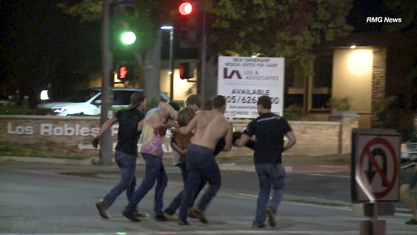 Junge Leute bringen einen Verletzten aus der Borderline-Bar in Thousand Oaks, Kalifornien, nachdem dort ein Mann auf feiernde Gäste geschossen hat.