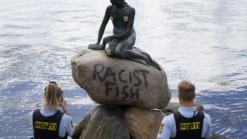 Polizeibeamte stehten an der Statue der kleinen Meerjungfrau, die von Unbekannten mit dem Schriftzug «Racist Fish» (Rassistischer Fisch) beschmiert wurde. Für politische Statements wurde die kleine Nixe schon häufiger missbraucht. (zu dpa "Stein der…