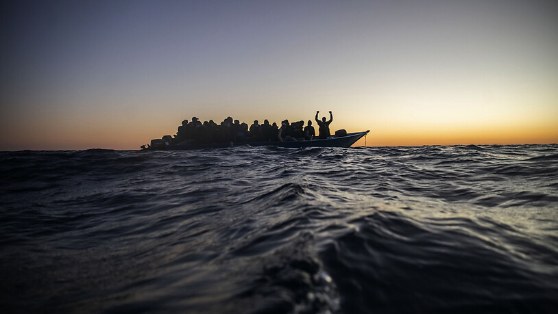 ARCHIV - Migranten aus verschiedenen afrikanischen Nationen warten in einem Boot auf Helfer der spanischen NGO Open Arms, die sich ihnen 122 Meilen vor der libyschen Küste im Mittelmeer nähern. Foto: Bruno Thevenin/AP/dpa