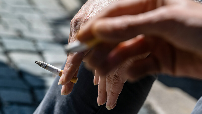 ARCHIV - Raucher halten eine brennende Zigarette in der Hand. Laut WHO erhöht Rauchen das Risiko, schwer an Covid-19 zu erkranken. Foto: Armin Weigel/dpa