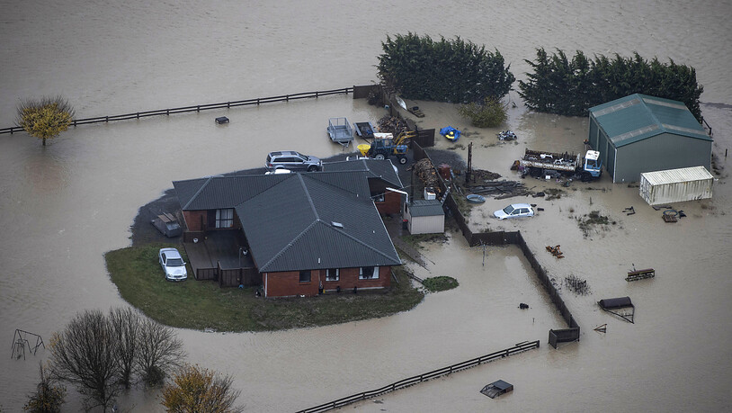 Ein Bauernhaus und ein Gebäude stehen unter Wasser. In Neuseeland sind Hunderte Menschen nach schweren Überschwemmungen in der Region Canterbury in Sicherheit gebracht worden. Foto: George Heard/New Zealand Herald/AP/dpa Foto: George Heard/New Zealand…