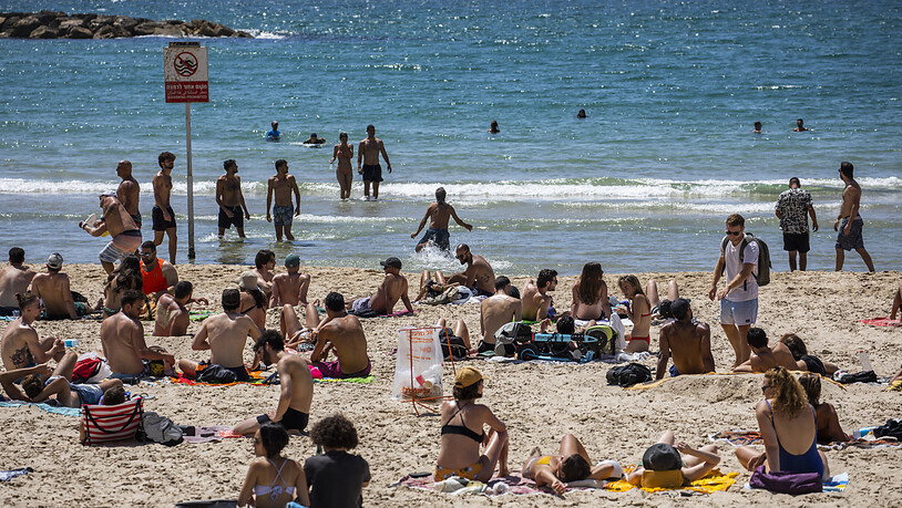 Menschen verbringen den Tag in der Sonne am Strand in Tel Aviv. Durch die fortgeschrittene Impfkampagne in Israel werden die Corona-Maßnahmen immer weiter aufgehoben. Foto: Ilia Yefimovich/dpa