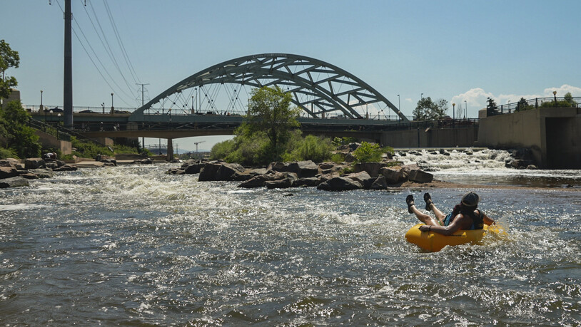 Menschen kühlen sich im Wasser ab, am Zusammenfluss von South Platte River und Cherry Creek. Am Nachmittag erreichte die Temperatur 35 Grad Celsius als Teil der Hitzewelle, die über den Westen der USA hinwegfegt. Foto: Brittany Peterson/AP/dpa