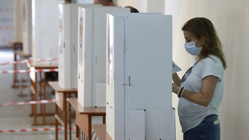 Menschen lesen während der Parlamentswahl in einem Wahllokal ihre Stimmzettel. Sieben Monate nach dem Krieg um die Konfliktregion Berg-Karabach wählt die krisengeschüttelte Südkaukasusrepublik Armenien ein neues Parlament. Foto: Sergei Grits/AP/dpa Foto:…