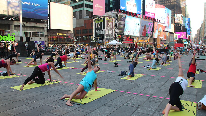 Menschen nehmen an einer gemeinsamen Yoga-Stunde inmitten des Times Square teil. Foto: Christina Horsten/dpa