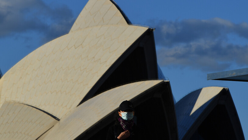 A pedestrian wearing a mask walks past the Sydney Opera House in Sydney, Saturday, June 26, 2021. All of greater Sydney, the Central Coast, the Blue Mountains and Wollongong regions will enter a two-week coronavirus lockdown until 9 July and new…