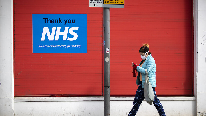 ARCHIV - Eine Frau geht im schottischen Edinburgh an einem Plakat mit der Aufschrift «Thank you NHS» vorbei. Foto: Jane Barlow/PA Wire/dpa