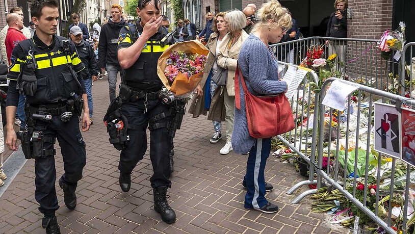 dpatopbilder - Polizisten bringen einen Blumenstrauß zu dem Blumenmeer für den Reporter Peter R. de Vries. Foto: Evert Elzinga/ANP/dpa
