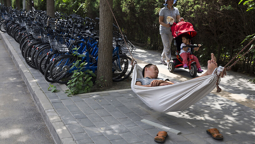 ARCHIV - Ein Mann schläft in einer Hängematte neben Fahrrädern einer Fahrrad-Verleihfirma. Viele junge Chinesen haben das Gefühl, alles hinschmeißen zu wollen. Foto: Ng Han Guan/AP/dpa