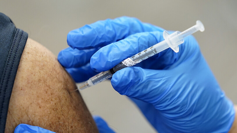 ARCHIV - Ein Mitarbeiter des Gesundheitswesens wird ein zweites Mal mit dem Impfstoff von Pfizer/Biontech geimpft. Foto: Paul Sancya/AP/dpa