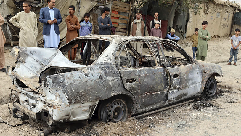 Anwohner betrachten ein durch einen Raketenangriff beschädigtes Fahrzeug. In der afghanischen Hauptstadt Kabul hat es einem Medienbericht zufolge einen Raketenangriff gegeben. Foto: Khwaja Tawfiq Sediqi/AP/dpa