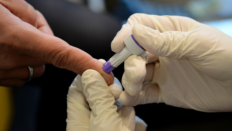 ARCHIV - Ein Arzt nimmt bei der Berliner Aids-Hilfe e.v. an dem Finger eines jungen Mannes Blut ab. In diesem Jahr sind auch angesichts der Corona-Pandemie weniger Menschen zum Testen gegangen. Foto: Britta Pedersen/dpa-Zentralbild/dpa