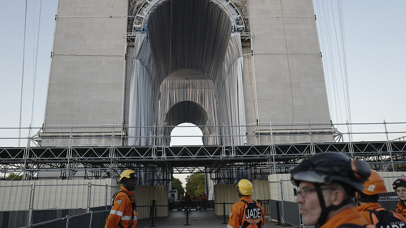 Arbeiter stehen bei der Verhüllung des Arc de Triomphe am frühen Sonntagmorgen vor dem Bauwerk. Foto: Rafael Yaghobzadeh/AP/dpa