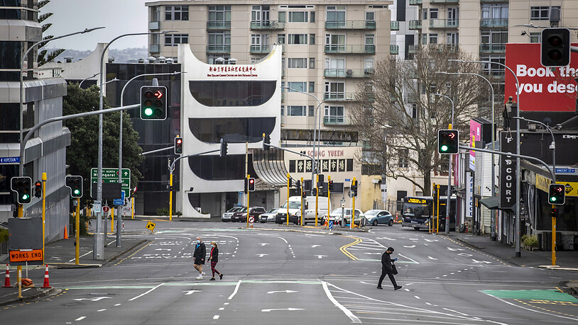 Menschen überqueren eine fast leere Straße im zentralen Geschäftsviertel von Auckland. Die Regierung von Ministerpräsidentin Jacinda Ardern gab am Montag bekannt, dass die neuseeländische Metropole eine weitere Woche im strikten Corona-Lockdown bleibt…