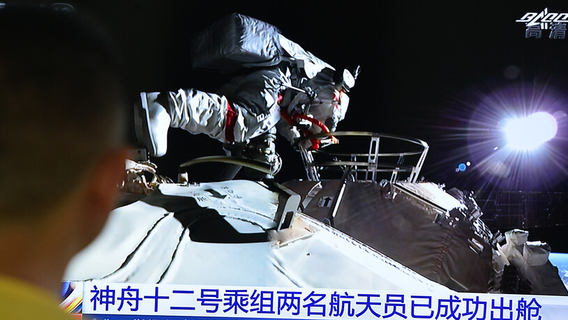 ARCHIV - Ein Mann verfolgt die Live-Übertragung über Astronauten des chinesischen Raumschiffs «Shenzhou 12», die in ihren Raumanzügen die Station verlassen 04.07.2021). Die drei Astronauten sind nach der Mission wieder auf der Erde gelandet. Foto:…