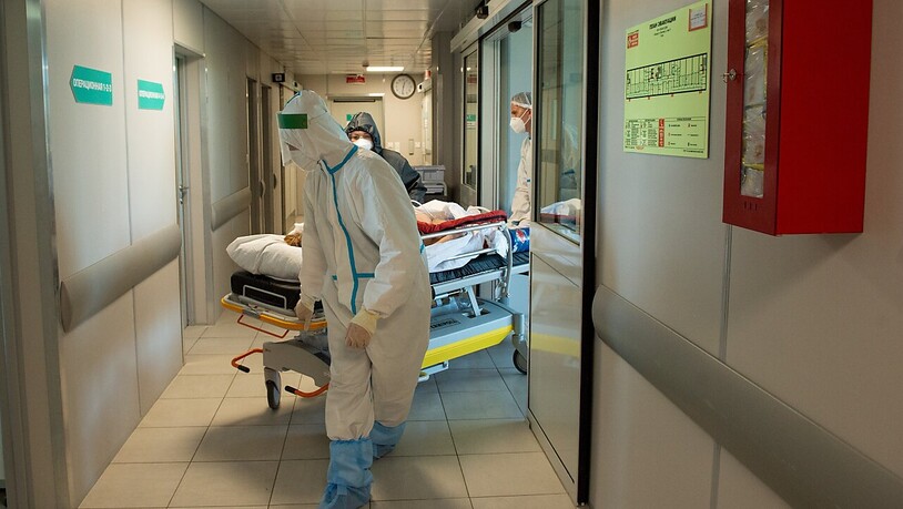 ARCHIV - Medizinische Mitarbeiter in Schutzkleidung schieben das Bett eines Corona-Patienten im städtischen Krankenhaus Nr. 52 in Moskau. (Archivbild) Foto: Denis Grishkin/Moscow News Agency/AP/dpa