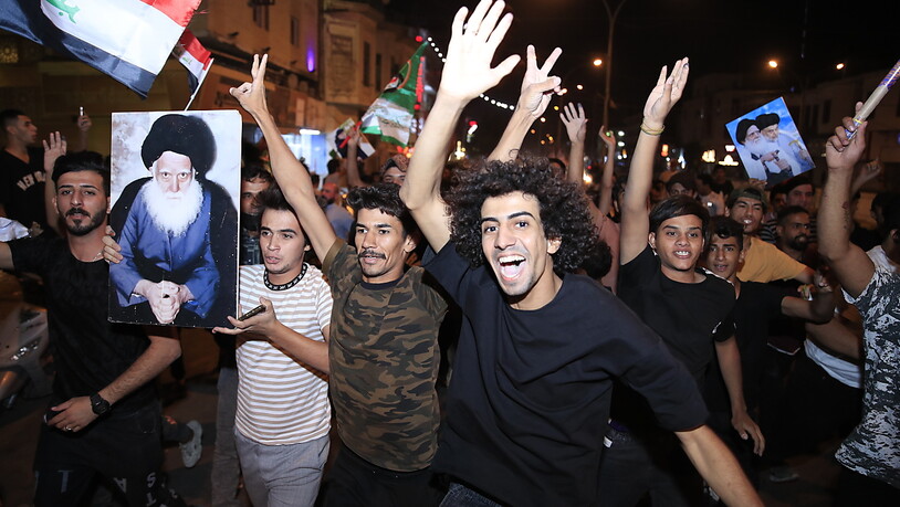 Anhänger des schiitischen Klerikers Al-Sadr feiern mit seinen Plakaten nach der Bekanntgabe der Ergebnisse der Parlamentswahlen auf dem Tahrir-Platz in Bagdad, Irak. Foto: Hadi Mizban/AP/dpa