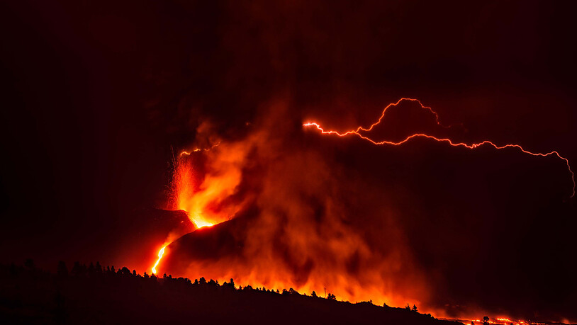 Ein vulkanischer Blitz über dem Vulkan Cumbre Vieja auf La Palma ist trotz des dichten, dunklen Rauchs, der aus dem Krater aufsteigt, von weitem sichtbar. Foto: Europa Press/EUROPA PRESS/dpa
