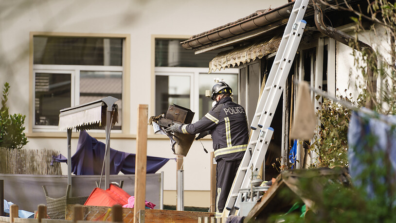 Ein Berner Kantonspolizist am Montag bei Aufräumarbeiten im vom Brand zerstörten Wohnhaus.