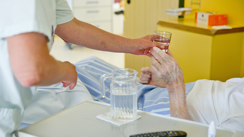 ARCHIV - Eine Krankenpflegerin reicht einem Patienten ein Glas Wasser. Durch den Brexit hat sich in Großbritannien der Pflegemangel deutlich verschärft. Vor allem bei der Betreuung von Behinderten fehle es an Personal, berichtete der «Observer» am…