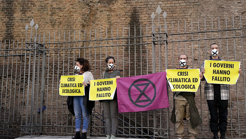 Klimaaktivisten von Extinction Rebellion ketten sich mit Fahrradschlössern an einen Zaun und halten Schilder während einer Demonstration vor dem G20-Gipfel hoch. Foto: Luca Bruno/AP/dpa