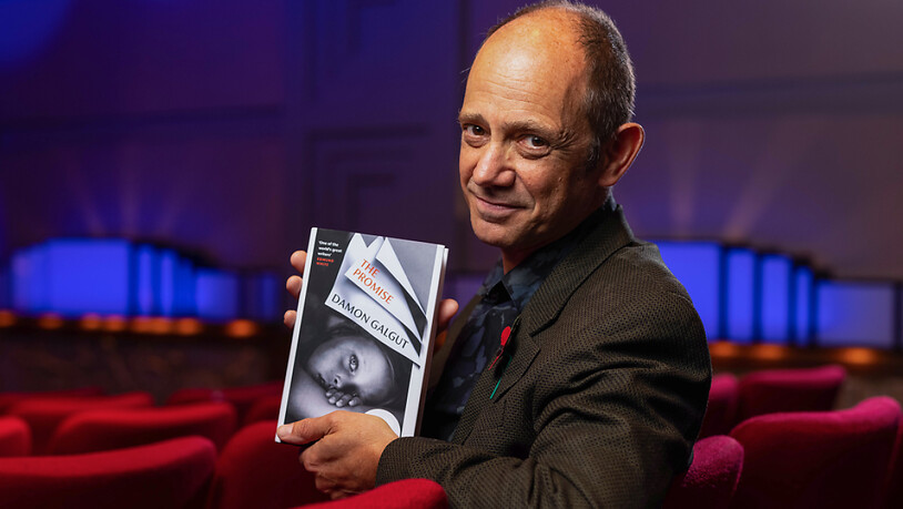 Damon Galgut, Schriftsteller aus Südafrika, hält bei der Verleihung des Booker Prize sein Buch «The Promise» hoch. Foto: David Parry/PA Wire/dpa - ACHTUNG: Nur zur redaktionellen Verwendung und nur mit vollständiger Nennung des vorstehenden Credits