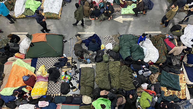 Menschen sind in der Notunterkunft in der Lagerhalle eines Logistikzentrums nahe der Grenze zu Polen untergebracht. Foto: Ulf Mauder/dpa