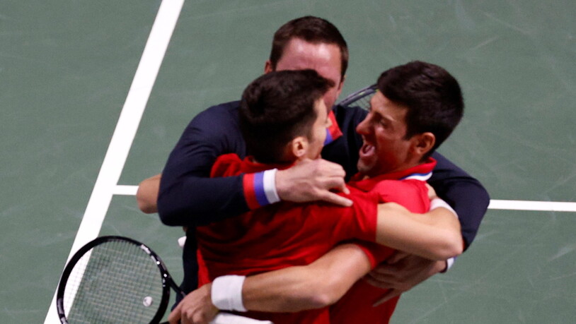 Novak Djokovic, Nikola Cacic (links) und Captain  Viktor Toricki  liegen sich nach dem entscheidenden Punkt in den Armen.