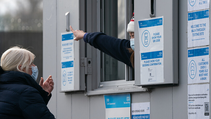 Ein Mitarbeiter eines Corona-Testzentrums weist einer Frau den Weg. Die neue Coronavirus-Variante Omikron ist in weiteren europäischen Ländern aufgetaucht. Foto: Joe Giddens/PA Wire/dpa