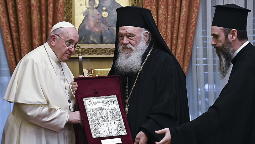 Papst Franziskus (l) tauscht Geschenke mit dem griechisch-orthodoxen Erzbischof Hieronymos II. (M) während eines Treffens im orthodoxen Erzbistum aus. Foto: Andreas Solaro/AFP POOL/AP/dpa