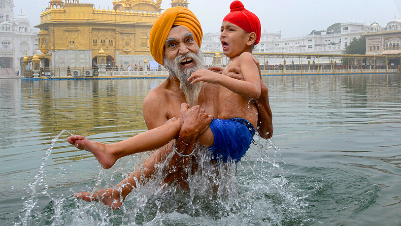dpatopbilder - Ein Sikh-Gläubiger nimmt mit einem Familienmitglied ein heiliges Bad im «Sarovar» während des Makar-Sankranti-Festes. Foto: Shiva Sharma/PTI/dpa