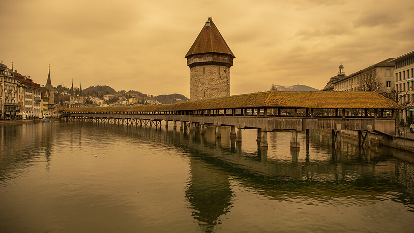 Die Kapellbrücke und der Wasserturm in Luzern sind wegen des Sandes aus der Sahara in gelbes Licht getaucht.
