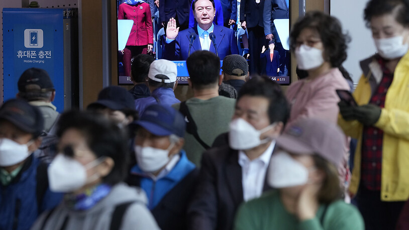 Menschen schauen auf einen Fernsehbildschirm, auf dem eine Live-Übertragung der Amtseinführungszeremonie des neu gewählten südkoreanischen Präsidenten Yoon Suk Yeol im Bahnhof von Seoul zu sehen ist. Foto: Ahn Young-Joon/AP/dpa