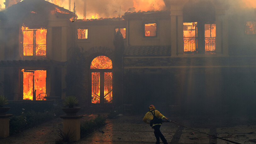 dpatopbilder - Ein Feuerwehrmann versucht, ein brennendes Gebäude in Laguna Niguel zu löschen. Im Süden des US-Bundesstaates Kalifornien hat ein Brand mehrere Häuser zerstört, darunter laut Medienberichten auch einige Villen im Millionenwert. Foto:…