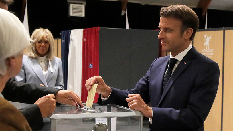 Emmanuel Macron, Präsident von Frankreich, wirft seinen Stimmzettel in eine Wahlurne, während seine Frau Brigitte Macron daneben steht. Die Französinnen und Franzosen wählen ein neues Parlament. Foto: Michel Spingler/AP Pool/dpa