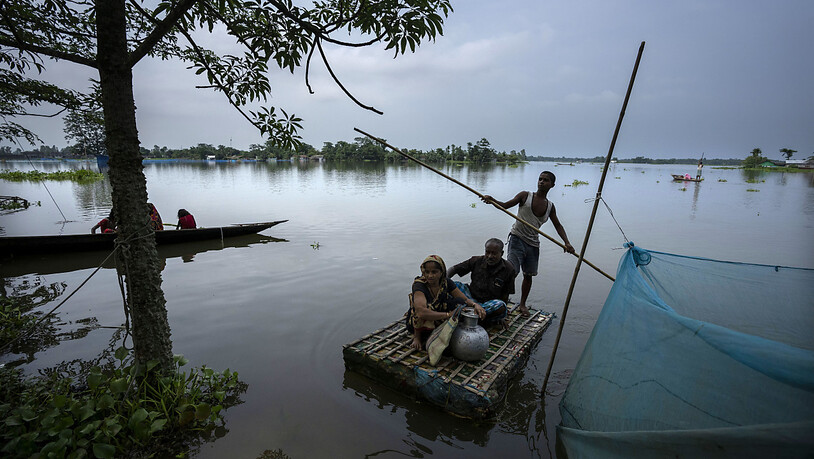 Von der Überschwemmung betroffene Menschen erreichen mit einem Behelfsboot ein sichereres und höher gelegenes Gebiet im Dorf Tarabari. Foto: Anupam Nath/AP/dpa