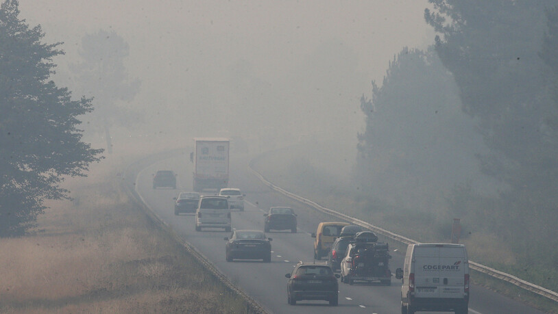 Lastwagen und Autos fahren auf der Autobahn A63, die durch einen Waldbrand 50 Kilometer südlich von Bordeaux verraucht ist. Hohe Waldbrandgefahr herrscht weiter auch in Südfrankreich. Foto: Bob Edme/AP/dpa