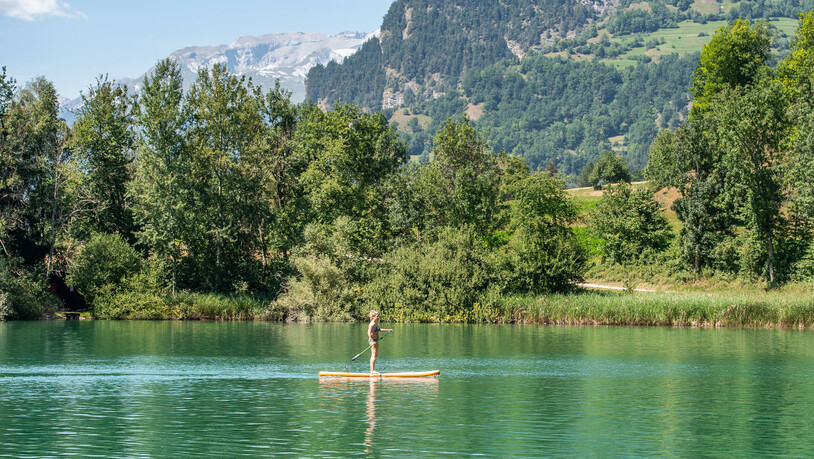 Sommerstimmung am Canovasee: Eine Frau gleitet auf einem Stand-up-Paddle übers Wasser.