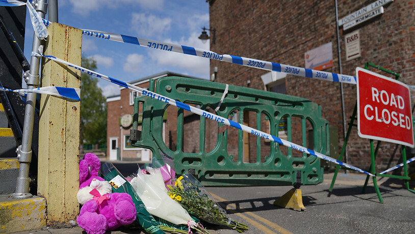 Blumen wurden in der Nähe des Tatorts, wo ein neunjähriges Mädchen an den Folgen einer mutmaßlichen Stichverletzung starb niedergelegt. Nach der Tötung eines neunjährigen Mädchens in England sucht die Polizei mit Fotos nach einem Verdächtigen. Foto: Joe…