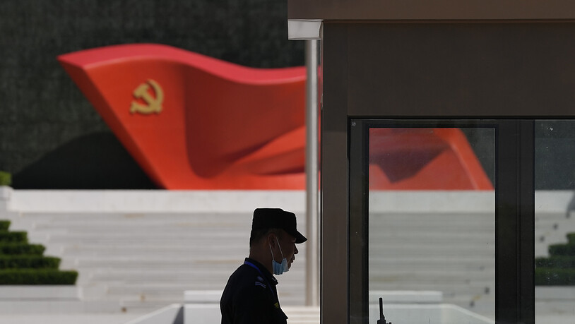 ARCHIV - Ein Sicherheitsbeamter steht neben einer Skulptur der Flagge der Kommunistischen Partei Chinas im Museum der Kommunistischen Partei Chinas. Foto: Ng Han Guan/AP/dpa